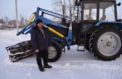 Универсальный водитель на универсальном тракторе расчищает дороги в Каякском сельсовете